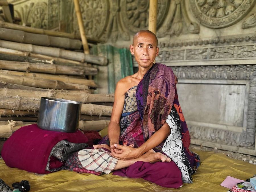 Thầy Minh Tuệ ngồi trang nghiêm trước tường điêu khắc của đền
